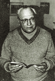 Black and White photo of Basil Lazer. He is standing, holding an open book.