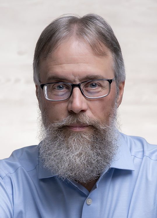 Photo of Lee Woofenden. He has glasses, is wearing a blue shirt and is looking directly at the viewer.