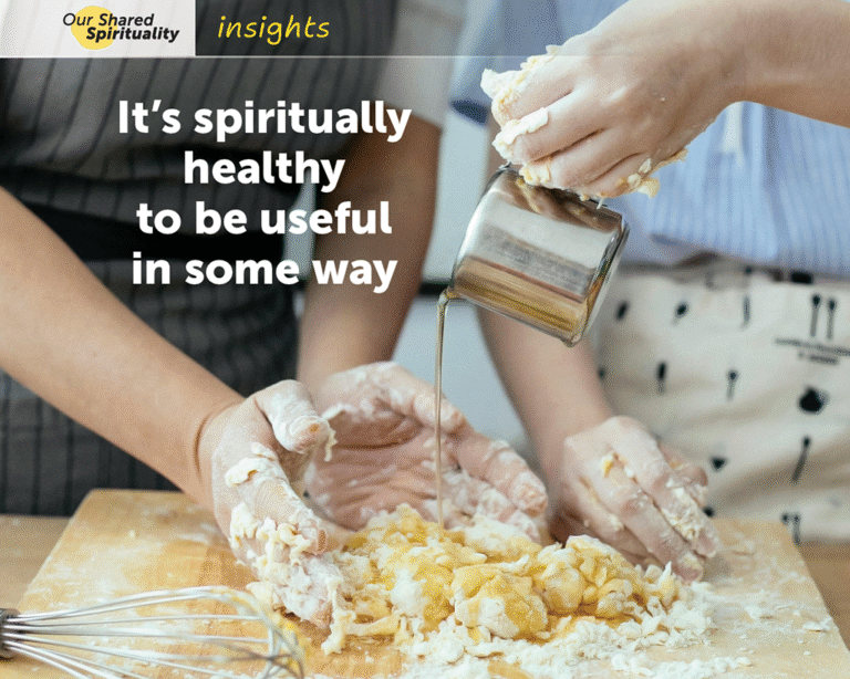 Two people wearing grey, blue and white clothing preparing pasta together. They are standing side by side behind a counter with a wooden board on it which has partially made pasta dough on it and a whisk to the left hand side. The person on the left is cupping their dough covered hands around the pasta dough while the person on the right drizzles olive oil onto the pasta dough from a small metal jug. White text on the image reads It’s spiritually healthy to be useful in some way. In a band along the top is a logo for 'Our Shared Spirituality' and the word 'insights'.